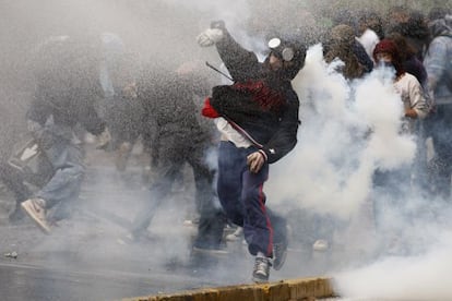 Un manifestante lanza una piedra a la policía entre gases lacrimógenos en Santiago.