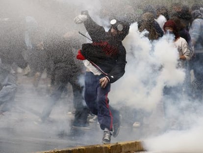 Un manifestante lanza una piedra a la policía entre gases lacrimógenos en Santiago.