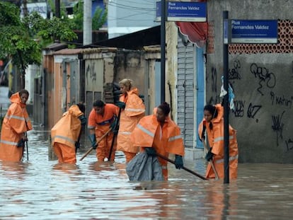 Garis tentam limpar bueiros de área inundada do Rio de Janeiro.