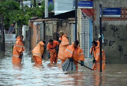 Garis tentam limpar bueiros de área inundada do Rio de Janeiro.