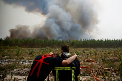 Dos bomberos se abrazan mientras trabajan para contener un incendio en Saint-Magne, este jueves.