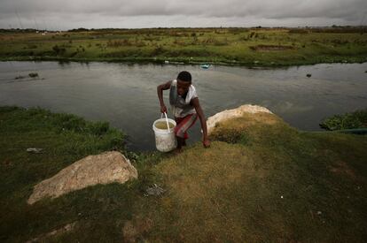 Un hombre llena su cubo de agua sin tratar en un río.