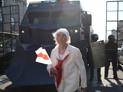 Una manifestante camina junto a las fuerzas de seguridad, este domingo en Minsk, la capital de Bielorrusia.