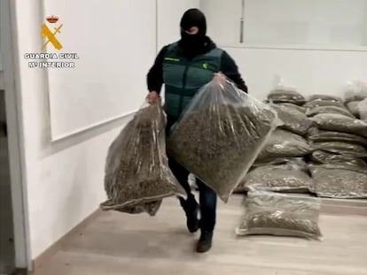 Un agente carga dos sacos de la marihuana incautada en Almería.