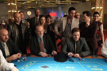 A scene from The Pelayos, with the actors Llu&iacute;s Homar and Daniel Br&uuml;hl seated at the table.