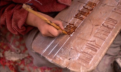 Un niño practica la escritura de caracteres tibetanos en una tablilla de madera.
