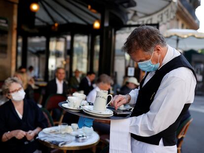 Garçom atende clientes em um café de Paris.