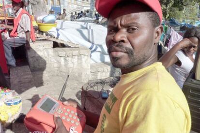 Joseph Joel vende llamadas desde su teléfono rojo en Puerto Príncipe.