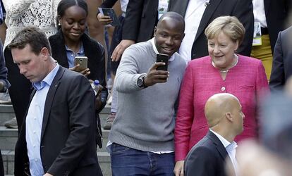 Angela Merkel posa con un visitante en el d&iacute;a de puertas abiertas de la canciller&iacute;a en Berl&iacute;n.