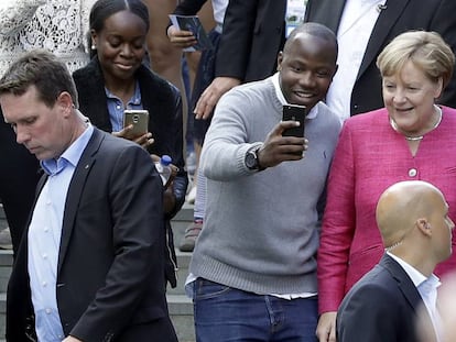 Angela Merkel posa con un visitante en el d&iacute;a de puertas abiertas de la canciller&iacute;a en Berl&iacute;n.