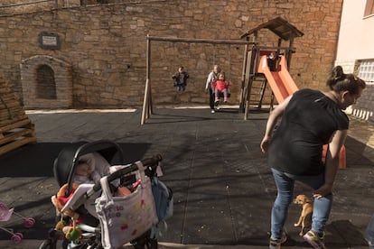 Vanesa Novella (derecha) juega con sus dos niños en el parque de Allepuz, Teruel.