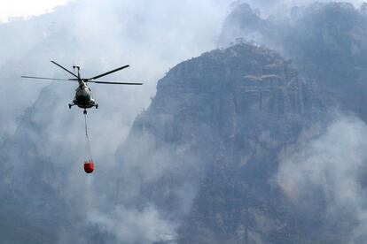 Dos helicópteros de la Comisión Nacional del Agua y otro más del Ejército han llegado para apoyar en las tareas. En la imagen, un helicóptero trabaja en las labores para apagar el incendio, el día de ayer.