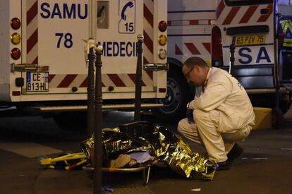 Un trabajador de rescate habla con un herido cerca de la sala Bataclan.