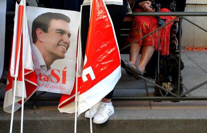 Cartel de Pedro Sánchez y banderas del PSOE de militantes que esperan en la entrada de la sede.