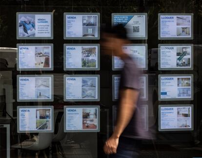 Un joven pasa frente a un escaparate de una agencia inmobiliaria en Barcelona.