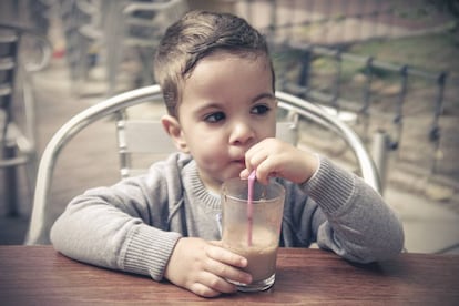 Un niño bebe un batido de cacao.