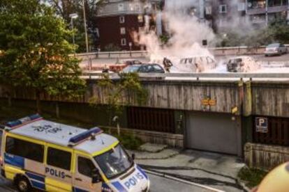 Policías extinguen el fuego en Husby.
