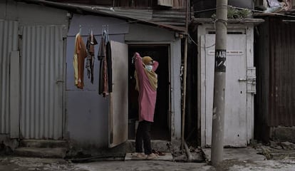 Una mujer indonesia residente en Kuala Lumpur (Malasia), se pone la mascarilla frente a la chabola donde vive. 