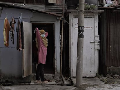 Una mujer indonesia residente en Kuala Lumpur (Malasia), se pone la mascarilla frente a la chabola donde vive. 