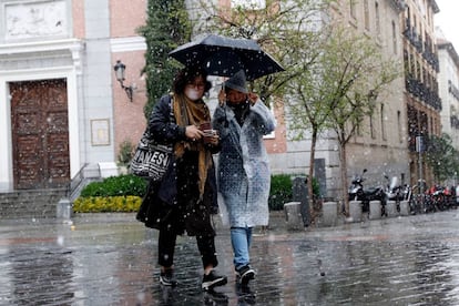 Unas turistas asiáticas se resguardan de la nieve en la calle Santiago de Madrid.