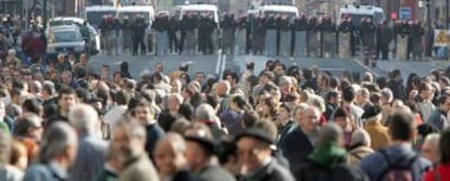 Al fondo, el cordón de la Ertzaintza que cortó el paso a la marcha convocada en Bilbao. En primer plano, algunos manifestantes.