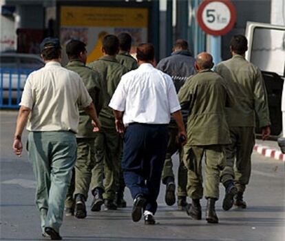 Seis soldados que ocupaban la isla Perejil son escoltados por oficiales marroquíes tras ser entregados por España.