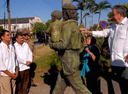 El presidente ecuatoriano escucha las observaciones de Raúl Castro ante la estatua del guerrillero.