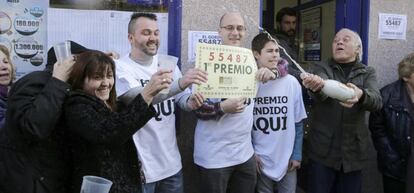 Varias personas celebrando el Gordo de la lotería de Navidad en la puerta de una administración.