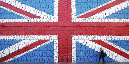 Una londinense camina junto a un mural del artista francés Tilt que incluye las letras de la canción de los Sex Pistols 'Anarchy in the UK'.