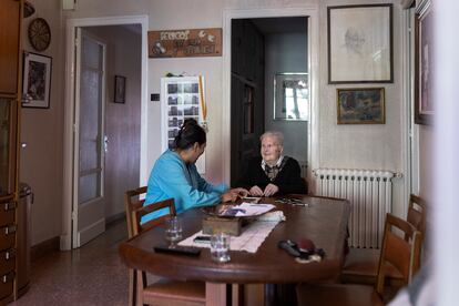 Rosa Prat juega con Marisol, trabajadora de ayuda a domicilio, al dominó, en su casa, en Manresa.