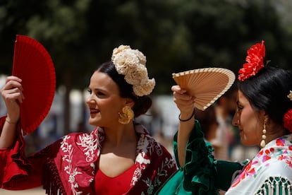 Varias mujeres vestidas de flamenca se protegen del sol con abanicos, este martes en la feria de Córdoba.