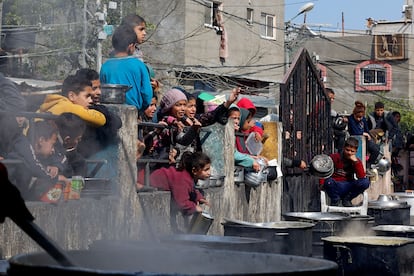 Palestinian children wait to receive food cooked by a charity kitchen amid shortages of food supplies, as the ongoing conflict between Israel and the Palestinian Islamist group Hamas continues, in Rafah