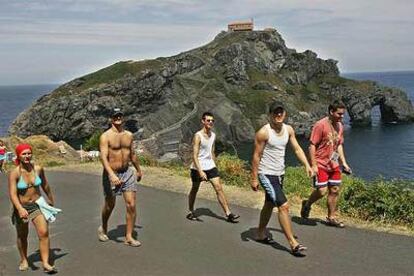 Un grupo de turistas pasea frente a la ermita de San Juan de Gaztelugatxe, en Bermeo (Vizcaya).