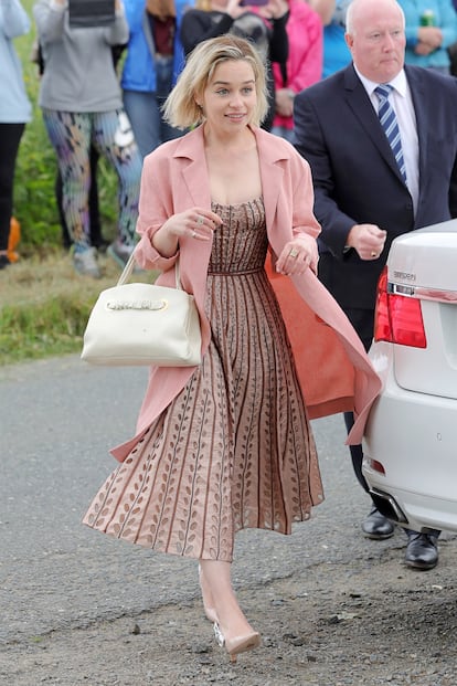 Vestida de largo midi en color rosa, Emilia Clarke ha conjuntado su diseño de tejido arrucado con un abrigo rosa y unos salones de charol de Dior.

 