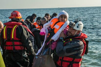 Sergio Soltero ayuda a desembarcar a una niña que ha llegado en una embarcación hinchable.