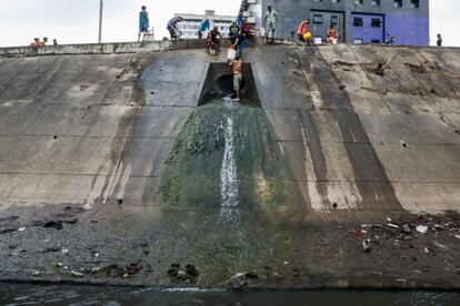 Un grupo de personas recoge agua desde una tubería de desagüe en la orilla del Río Guaire Caracas (Venezuela). El río Guaire son las cloacas de Caracas, el lugar a donde van a parar todas las aguas fecales de la ciudad, tiñendo de color marrón su recorrido e inundando el ambiente de un hedor nauseabundo a su paso.