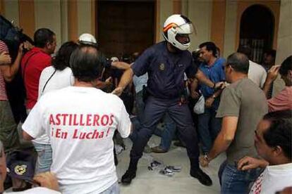 Un policía trataba ayer de impedir que trabajadores del astillero de Sevilla entraran en el Ayuntamiento de la capital.