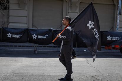 Un hombre, vestido de negro, lleva una bandera del mismo color del partido Renovación Nacional, del que Piñera fuera presidente entre 2001 y 2004.
