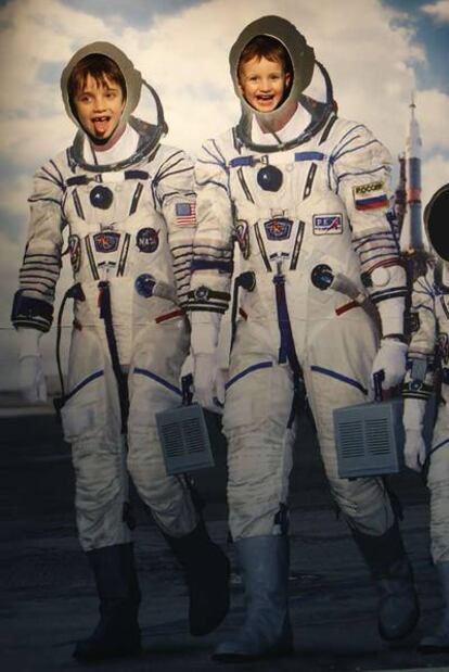 Dos niños se fotografían en un mural de astronautas a la salida de la exposición.