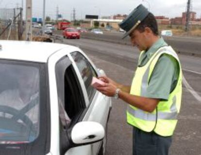 Un agente de Tr&aacute;fico pide la documentaci&oacute;n a un conductor durante un control de carretera.