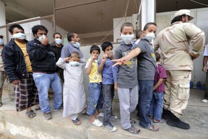 Varios niños aguardan con máscaras en la fila para ver el cadáver de Gadafi en Misrata.