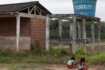 Crianças brincam perto de esqueleto de obra na aldeia Canamary. Conhecida como "chafariz", a estrutura tem três vasos sanitários e seis chuveiros completamente abandonados. A estrutura deixou de ser usada menos de um ano depois de ter sido construída porque o motor que levava a água do subsolo para a caixa d'água não passou por manutenção. O local está abandonado, lotado de fezes de animais. A mesma situação foi vista em todas as aldeias visitadas pelo EL PAÍS na Terra Indígena Alto Rio Purus.