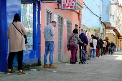 Varios ciudadanos hacen cola delante de un supermercado, este sábado, en Ferrol (A Coruña).