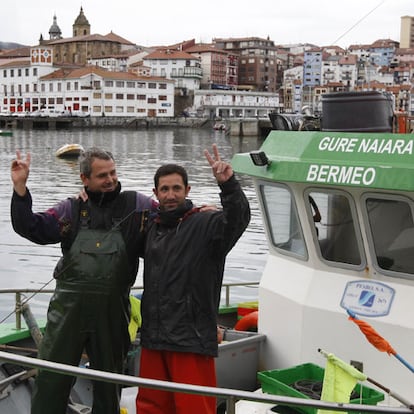 Dos pescadores celebran sobre su embarcación en el puerto de Bermeo el fin del secuestro.