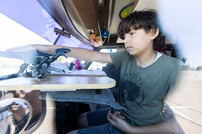 Ayden, de 13 años, se divierte con un dinosaurio de juguete sobre su “pupitre”, ubicado sobre el volante de la autocaravana. 