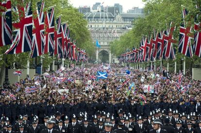 Británicos esperan el paso de la reina Isabel II en su camino hacia el palacio de Buckingham.