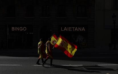 Dos personas marchan con banderas de España durante una protesta sobre la igualdad salarial y las condiciones de la Policía, en el centro de Barcelona, el 10 de noviembre.