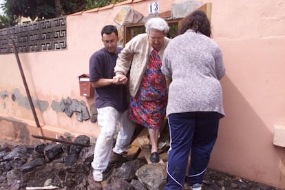 Una pareja ayuda a una anciana a salir de la calle, cubierta de rocas, después de las lluvias torrenciales que arrasaron las calles de Santa Cruz de Tenerife el 31 de marzo de 2002. Las riadas dejaron ocho muertos y la imagen de una ciudad desolada.