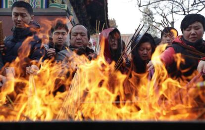 Un grupo de personas quema incienso en una hoguera en templo de Yonghegong Lama, en Pekín. La quema de incienso es una tradición en búsqueda de la fortuna para el Año Nuevo.