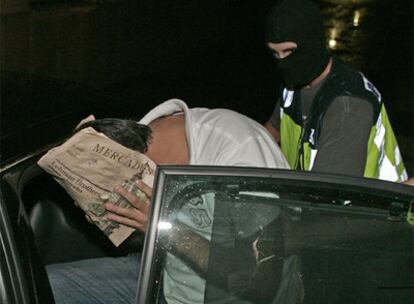 Uno de los detenidos se cubre el rostro a su salida de los juzgados de Sevilla